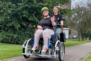 Zwei Personen fahren mit dem Rollstuhlfahrrad.